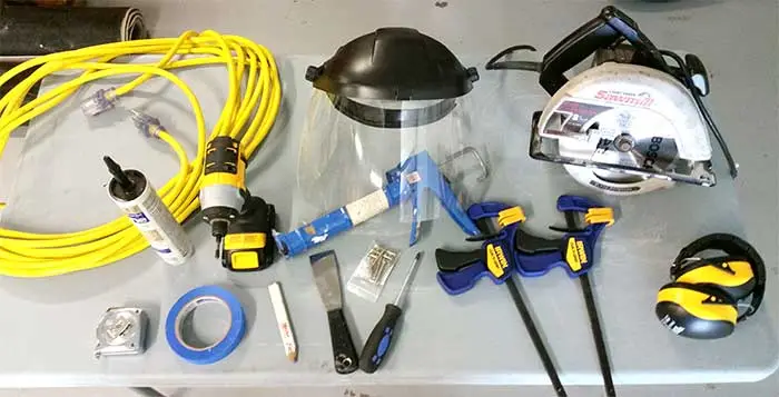 Tools for installing a RANGER pet door, including safety equipment, saw, clamps, screw gun, etc.